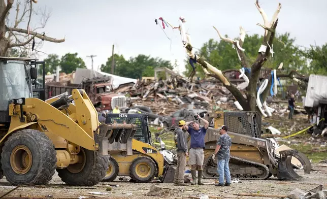 Workers stand near a home destroyed by a tornado Tuesday, May 21, 2024, in Greenfield, Iowa. (AP Photo/Charlie Neibergall)
