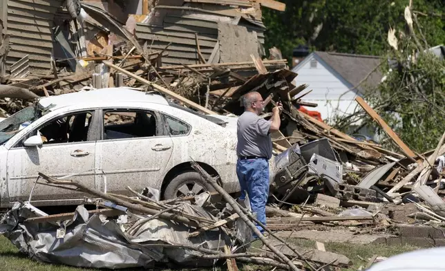 A man takes a photo in front of a tornado damaged home, Wednesday, May 22, 2024, in Greenfield, Iowa. (AP Photo/Charlie Neibergall)