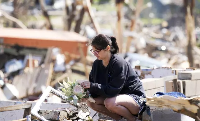 Kimberly Ergish holds flowers as she cleans out belongs from her tornado damaged home, Wednesday, May 22, 2024, in Greenfield, Iowa. (AP Photo/Charlie Neibergall)