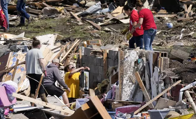 Local residents clean up debris from a tornado damaged home, Wednesday, May 22, 2024, in Greenfield, Iowa. (AP Photo/Charlie Neibergall)