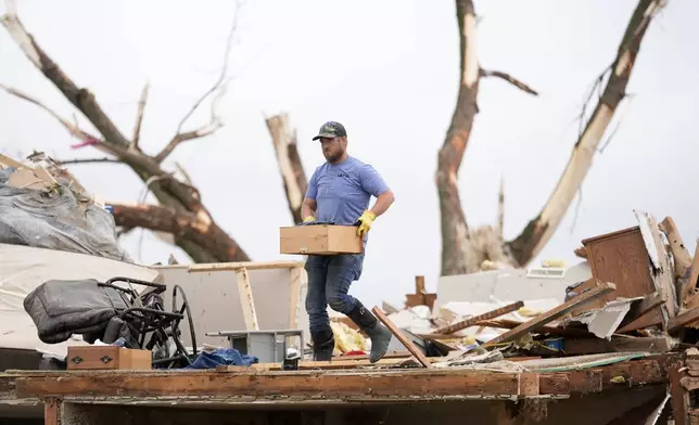 A man sorts through the remains of a tornado-damaged home, Tuesday, May 21, 2024, in Greenfield, Iowa. (AP Photo/Charlie Neibergall)