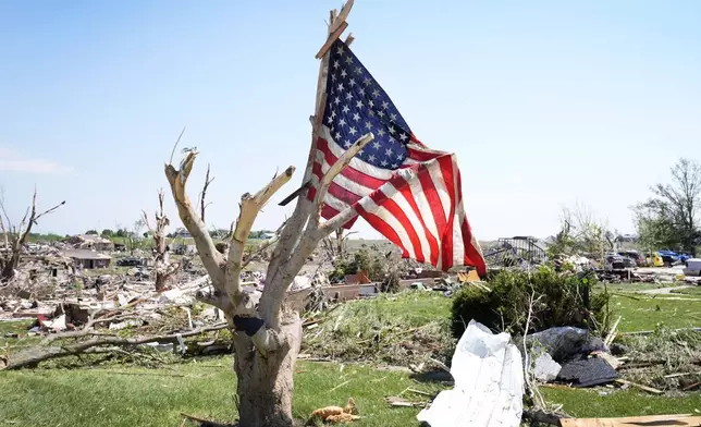 A flag hangs in a tree near tornado damaged homes, Wednesday, May 22, 2024, in Greenfield, Iowa. (AP Photo/Charlie Neibergall)