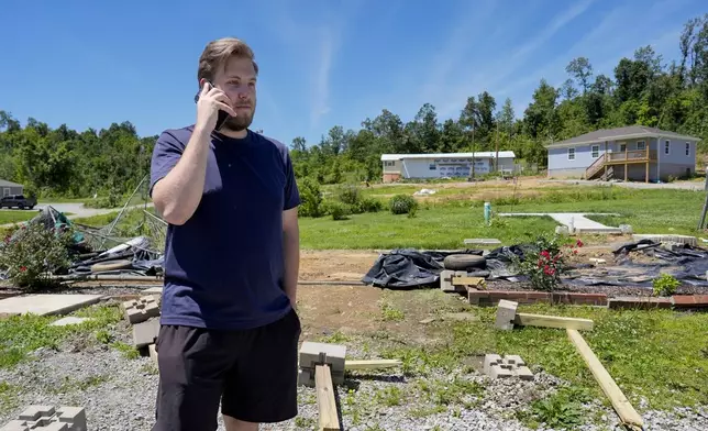 Devin Johnson uses his phone where his house once stood along Barnsley Loop, Tuesday, May 28, 2024, in Madisonville, Ky. A series of powerful storms hit the central and southern U.S. over the Memorial Day holiday weekend. (AP Photo/George Walker IV)