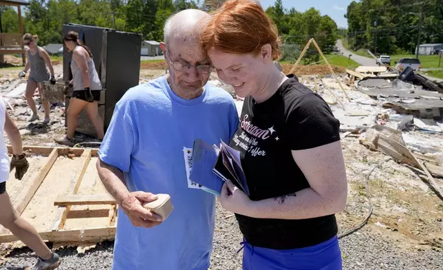 Jesse Johnson, left, and Haley Loukota, right, celebrate as they find their belongings at their demolished home along Barnsley Loop, Tuesday, May 28, 2024, in Madisonville, Ky. A series of powerful storms hit the central and southern U.S. over the Memorial Day holiday weekend. (AP Photo/George Walker IV)