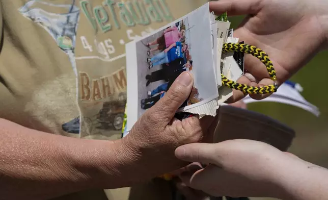 Haley Loukota, right, hands family photos to to Lois Johnson after they were found in storm debris along Barnsley Loop, Tuesday, May 28, 2024, in Madisonville, Ky. A series of powerful storms hit the central and southern U.S. over the Memorial Day holiday weekend. (AP Photo/George Walker IV)