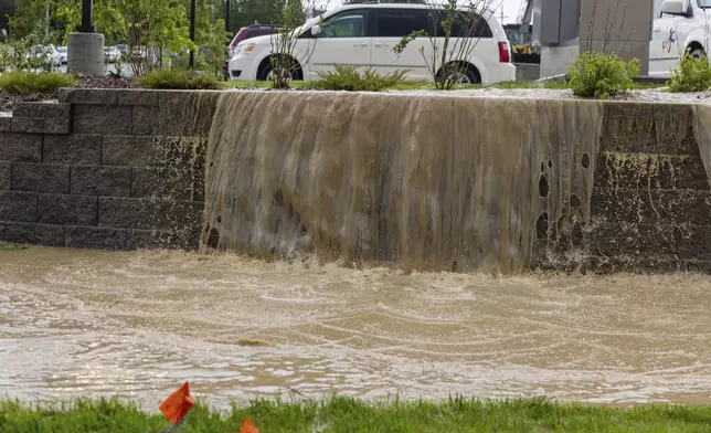 Water pours out of a parking lot onto the ground in Omaha, Neb. on Tuesday, May 21, 2024. (Chris Machian /Omaha World-Herald via AP)