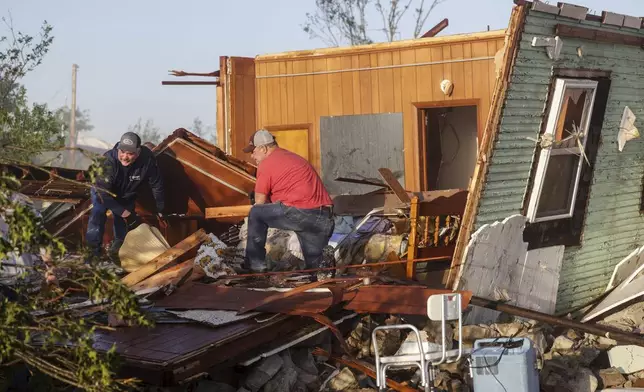Carl Kelley and Jon Reynolds search through Kelley's mother's home after it was damaged by a severe storm, Tuesday, May 7, 2024 in Barnsdall, Okla. A tornado destroyed homes, forced the evacuation of a nursing home and toppled trees and power lines when it roared through the small Oklahoma town. (Mike Simons/Tulsa World via AP)