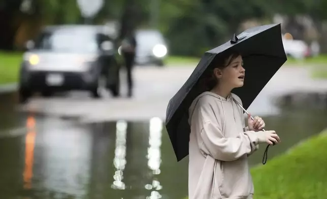 Zoe Kovar walks through her neighborhood in North Woodland Hills to survey the area after severe flooding, Thursday, May 2, 2024, in the Houston neighborhood of Kingwood, Texas. (Jason Fochtman/Houston Chronicle via AP)