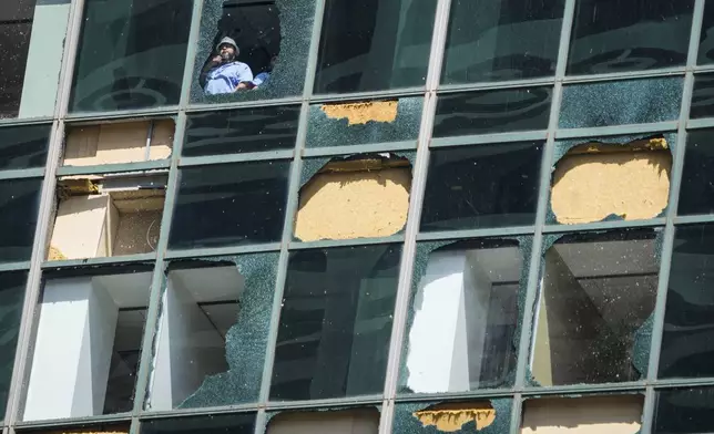 Workers clean out shattered glass at the Wells Fargo building as clean up from the previous week's storm continues in downtown Houston, Monday, May 20, 2024. The city closed off streets in a six-block exclusion zone downtown, from McKinney to Polk and from Smith to Travis to ease traffic around the area where broken glass and debris are prevalent. (Brett Coomer/Houston Chronicle via AP)