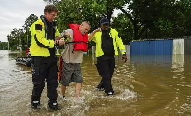 Tim McCanon, center, is rescued by the Community Fire Department during severe flooding on Friday, May 3, 2024, in New Caney, Texas. (Raquel Natalicchio/Houston Chronicle via AP)