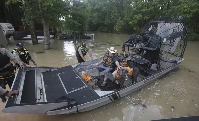 Texas Parks &amp; Wildlife Department game wardens use a boat to rescue residents from floodwaters in Liberty County, Texas, on Saturday, May 4, 2024. (AP Photo/Lekan Oyekanmi)