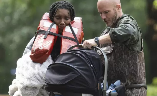 A woman is handed her child after being evacuated by boat from her homes with the help of deputies with the Montgomery County Sheriff's Office, Friday, May 3, 2024, in Conroe, Texas. Torrential rain is inundating southeastern Texas, forcing schools to cancel classes and closing numerous highways around Houston. (Jason Fochtman/Houston Chronicle via AP)