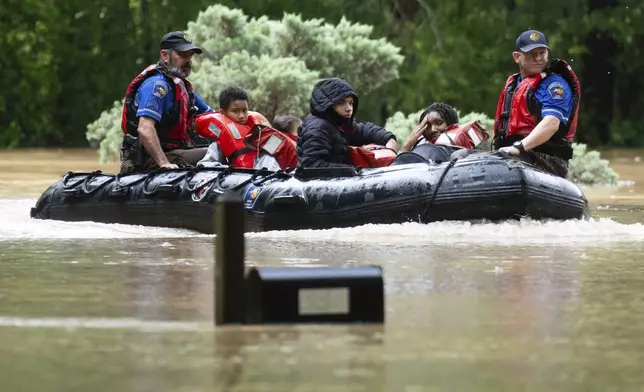 A woman reacts as she and others are evacuated by boat from their homes by Montgomery County Sheriff's Office deputies, Friday, May 3, 2024, in Conroe, Texas. Torrential rain is inundating southeastern Texas, forcing schools to cancel classes and closing numerous highways around Houston. (Jason Fochtman/Houston Chronicle via AP)