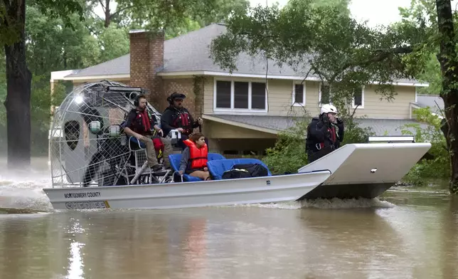 A woman is rescued by airboat from her home by Montgomery County Sheriff's Office deputies on River Plantation Drive, Friday, May 3, 2024, in Conroe, Texas. Torrential rain is inundating southeastern Texas, forcing schools to cancel classes and closing numerous highways around Houston. (Jason Fochtman/Houston Chronicle via AP)