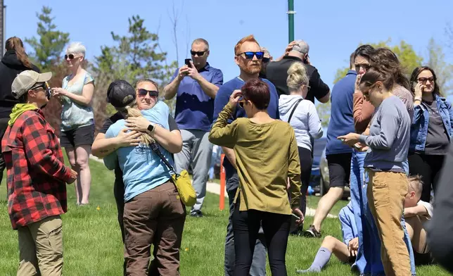 People gather at a site designated for parent and student reunifications following a report of a armed person outside Mount Horeb Middle School in Mount Horeb, Wis., Wednesday, May 1, 2024. (John Hart/Wisconsin State Journal via AP)