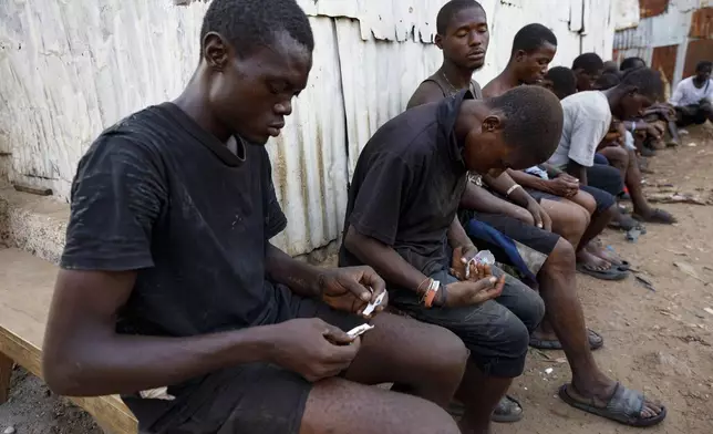 A young man rolls Kush as other users sleep at a hideout in Freetown, Sierra Leone, Monday, April 29, 2024. Sierra Leone declared a war on the cheap synthetic drug, calling it an epidemic and a national threat. The drug is ravaging youth, and healthcare services are severely limited. (AP Photo/ Misper Apawu)