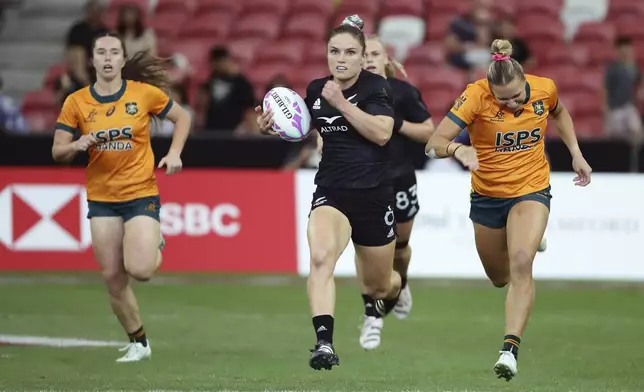 Michaela Blyde of New Zealand, center, runs and scores a try during the women's World Rugby Sevens Series 2024 cup final between Australia and New Zealand in Singapore, on Sunday, May 5, 2024. (AP Photo/Suhaimi Abdullah)