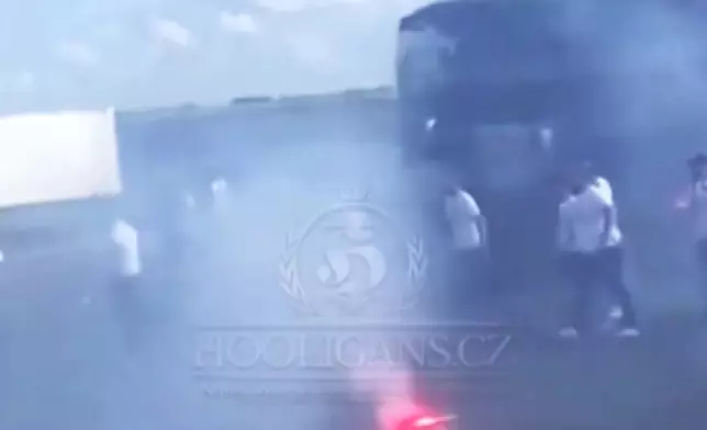 In this photo taken from video released by Hooligans.cz, people dressed in black fight against people dressed in white, near Fresnes-Les-Montauban, France, Saturday, May 25, 2024. Lyon and Paris Saint-Germain supporters clashed on a highway leading to the venue of the French Cup final a few hours before kickoff on Saturday.(Hooligans.cz via AP)