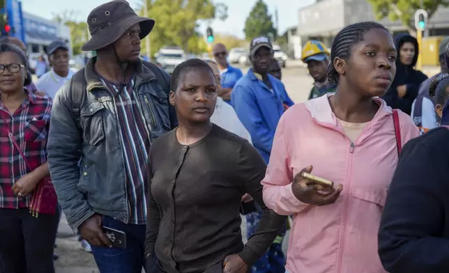 Onlookers gather near the site of a building collapse in George, South Africa, Wednesday, May 8, 2024. Rescue teams searching for dozens of construction workers missing after a multi-story apartment complex collapsed in the coastal city have brought out more survivors as the operation entered a second night of desperate work to find anyone alive in the mangled wreckage.(AP Photo/Jerome Delay)