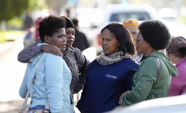 A relative, left, of a trapped person, is consoled at the site of a building collapse in George, South Africa, Wednesday, May 8, 2024. Rescue teams are into a third day searching for dozens of construction workers buried in the rubble of an unfinished five-story apartment building that collapsed in South Africa. (AP Photo/Nardus Engelbrecht)