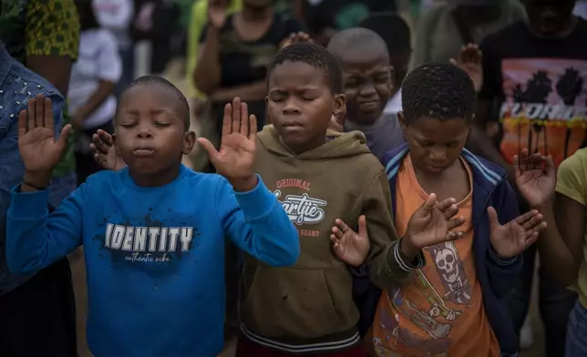 Children pray during an election meeting organized by Ukhonto weSizwe party in Mpumalanga, near Durban, South Africa, Saturday, May 25, 2024, ahead of the 2024 general elections scheduled for May 29. (AP Photo/Emilio Morenatti)