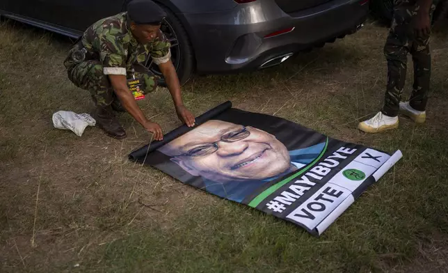 A military officer rolls up a poster of former South African President Jacob Zuma during an election meeting in Durban, South Africa, Saturday, May 25, 2024, in anticipation of the 2024 general elections scheduled for May 29. (AP Photo/Emilio Morenatti)