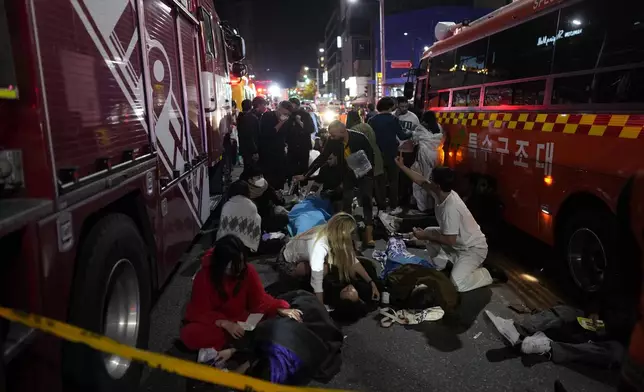 FILE - Injured people are helped at a street near the scene of a crush in Seoul, South Korea, on Oct. 30, 2022. South Korea’s parliament on Thursday, May 2, 2024 approved legislation mandating a new, independent investigation into the 2022 Halloween crush in Seoul that killed 159 people. (AP Photo/Lee Jin-man, File)