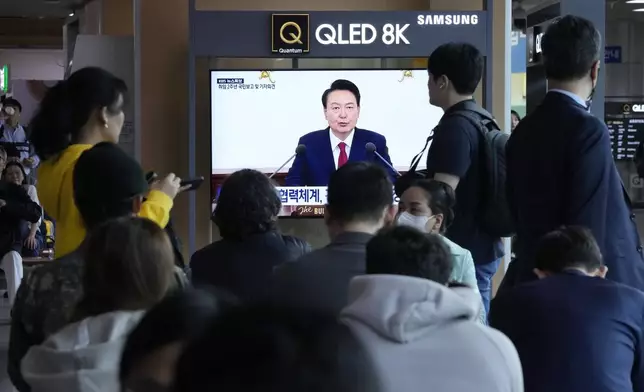People watch a TV screen showing the live broadcast of South Korean President Yoon Suk Yeol's press conference, at the Seoul Railway Station in Seoul, South Korea, Thursday, May 9, 2024. (AP Photo/Ahn Young-joon)