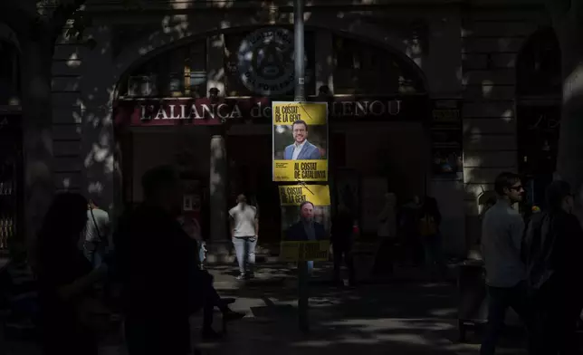 People walk past electoral posters showing a portrait of Catalan president and ERC candidate Pere Aragonès in downtown Barcelona, Spain, Thursday, May 9, 2024. Some nearly 6 million Catalans are called to cast ballots in regional elections on Sunday that will surely have reverberations in Spain's national politics. (AP Photo/Emilio Morenatti)