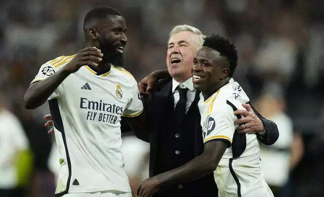 Real Madrid's head coach Carlo Ancelotti, centre, celebrates with his players Vinicius Junior, right, and Antonio Rudiger after winning the Champions League semifinal second leg soccer match between Real Madrid and Bayern Munich at the Santiago Bernabeu stadium in Madrid, Spain, Wednesday, May 8, 2024. Real Madrid won 2-1. (AP Photo/Jose Breton)