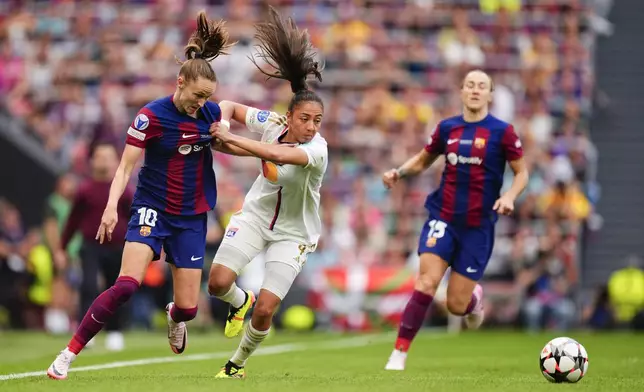 Barcelona's Caroline Graham Hansen, left, and Lyon's Selma Bacha, center, compete for the ball during the women's Champions League final soccer match between FC Barcelona and Olympique Lyonnais at the San Mames stadium in Bilbao, Spain, Saturday, May 25, 2024. (AP Photo/Jose Breton)
