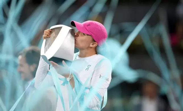 Poland's Iga Swiatek kisses the trophy after winning the women's final match against Aryna Sabalenka of Belarus, at the Mutua Madrid Open tennis tournament in Madrid, Spain, Saturday, May 4, 2024. (AP Photo/Bernat Armangue)