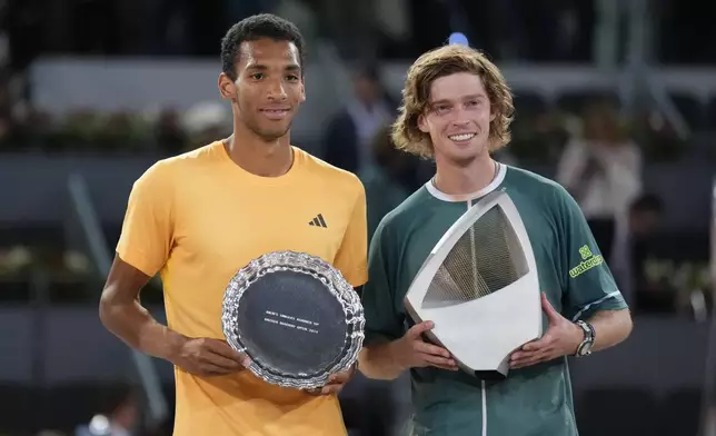 Andrey Rublev, of Russia, right, holds his trophy after winning against Felix Auger-Aliassime, of Canada, left, in the Madrid Open men's final match in Madrid, Spain, Sunday, May 5, 2024. (AP Photo/Manu Fernandez)