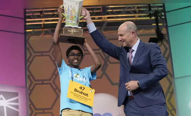 Bruhat Soma, 12, of Tampa, Fla., accepts the trophy from E.W. Scripps Company president and CEO Adam Symson after winning the Scripps National Spelling Bee, in Oxon Hill, Md., Thursday, May 30, 2024. (AP Photo/Jacquelyn Martin)