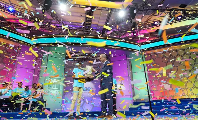 Bruhat Soma, 12, of Tampa, Fla., accepts the trophy from E.W. Scripps Company president and CEO Adam Symson after winning the Scripps National Spelling Bee, in Oxon Hill, Md., Thursday, May 30, 2024. (AP Photo/Jacquelyn Martin)