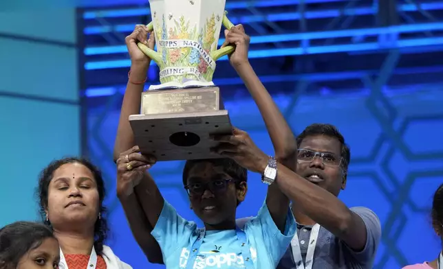 Bruhat Soma, 12, of Tampa, Fla., holds the trophy with his parents after winning the Scripps National Spelling Bee, in Oxon Hill, Md., Thursday, May 30, 2024. (AP Photo/Jacquelyn Martin)