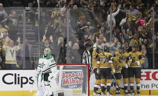 Dallas Stars goaltender Jake Oettinger (29) looks on while Vegas Golden Knights right wing Michael Amadio (22) celebrates with teammates after his goal during the first period in Game 4 of an NHL hockey Stanley Cup first-round playoff series Monday, April 29, 2024, in Las Vegas. (AP Photo/Ian Maule)