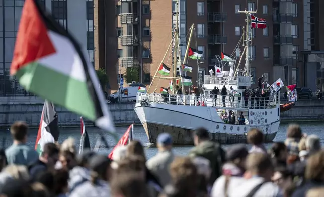 Demonstrators carrying Palestinian flags look on as the Ship to Gaza boat 'Handala' arrives at the port of Malmö, Sweden, Wednesday, May 8, 2024. The visit by Ship to Gaza and the demonstration in connection with it are part of the protests against Israel's participation in the 68th edition of Eurovision Song Contest (ESC) at Malmö Arena. (Johan Nilsson/TT News Agency via AP)