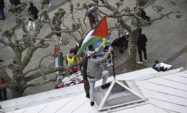 Protestors fix a Palestinian and Swedish flag atop of a building during a Stop Israel demonstration, between Stortorget and Mölleplatsen in Malmö, Sweden, Thursday, May 9, 2024. There have been calls for Israel to be excluded from the Eurovision Song contest because of its conduct in its war against Hamas. (Johan Nilsson/TT News Agency via AP)