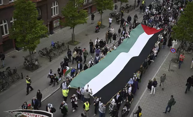 Protesters carry a giant Palestinian flag in Malmo, Sweden, Thursday, May 9, 2024. Several protests are expected against Israel's participation in the 68th edition of the Eurovision Song Contest (ESC) at the Malmo Arena. (Johan Nilsson/TT News Agency via AP)