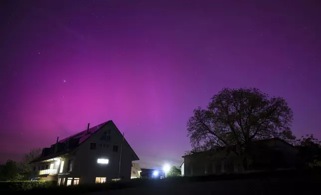 Northern lights glow in the night sky above the village of Daillens, Switzerland, early Saturday, May 11, 2024. (Laurent Gillieron/Keystone via AP)