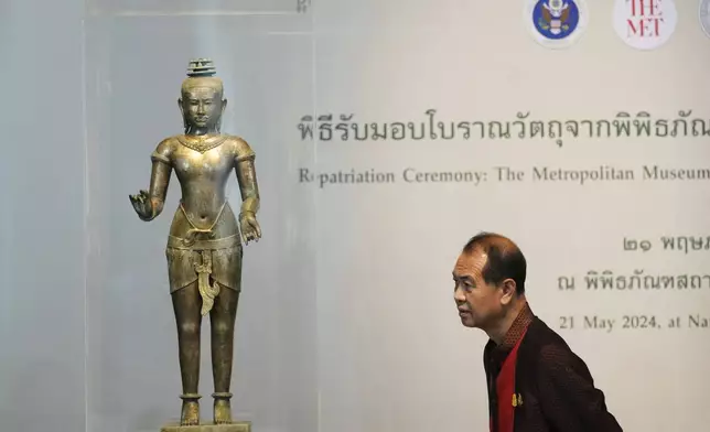 Thai person looks at a standing Shiva sculpture from the 11th century during repatriation ceremony at National Museum in Bangkok, Thailand, Tuesday, May 21, 2024. Thailand's National Museum hosted a welcome-home ceremony Tuesday for two ancient statues that were illegally trafficked from Thailand by a British collector of antiquities and were returned from the collection of New York’s Metropolitan Museum of Art. (AP Photo/Sakchai Lalit)