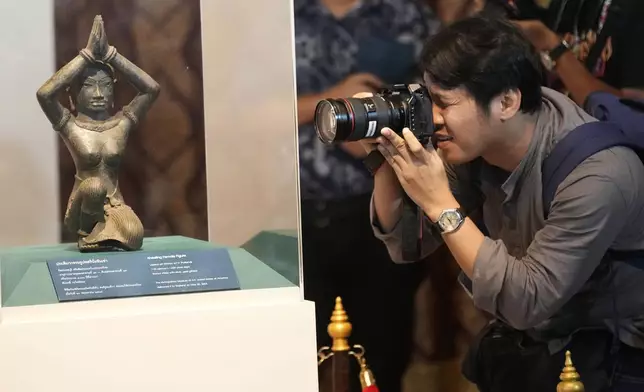 Thai photographer takes a picture of the ancient bronze kneeling woman sculpture during a repatriation ceremony at National Museum in Bangkok, Thailand, Tuesday, May 21, 2024. Thailand's National Museum hosted a welcome-home ceremony Tuesday for two ancient statues that were illegally trafficked from Thailand by a British collector of antiquities and were returned from the collection of New York’s Metropolitan Museum of Art. (AP Photo/Sakchai Lalit)