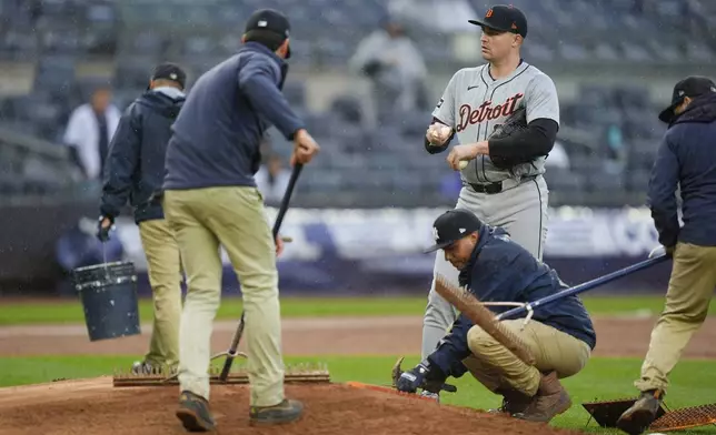 Detroit Tigers pitcher Tarik Skubal, top right, looks on as the grounds crew maintains the mound amid rainfall during the sixth inning of a baseball game against the New York Yankees at Yankee Stadium, Sunday, May 5, 2024, in New York. (AP Photo/Seth Wenig)