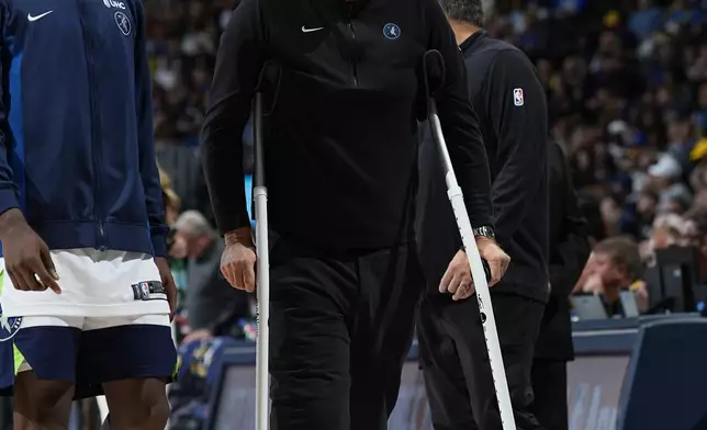 Minnesota Timberwolves head coach Chris Finch, right, walks with crutches as guard Anthony Edwards, left, looks on in the second half of Game 1 of an NBA basketball second-round playoff series against the Denver Nuggets, Saturday, May 4, 2024, in Denver. (AP Photo/David Zalubowski)