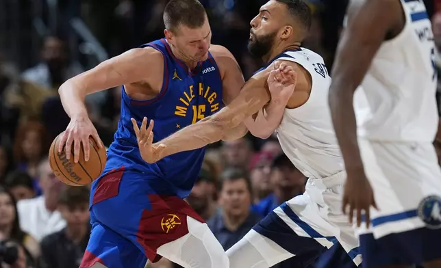Denver Nuggets center Nikola Jokic, left, drives to the basket as Minnesota Timberwolves center Rudy Gobert defends in the second half of Game 1 of an NBA basketball second-round playoff series Saturday, May 4, 2024, in Denver. (AP Photo/David Zalubowski)