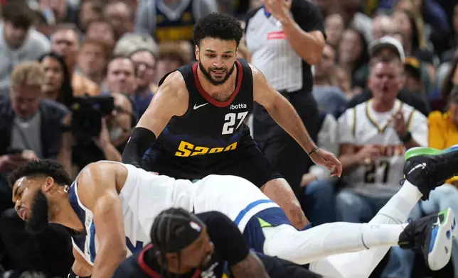 Denver Nuggets guard Jamal Murray, back, looks on as Minnesota Timberwolves center Karl-Anthony Towns, center, falls to the fall after colliding with Nuggets guard Kentavious Caldwell-Pope during the first half of Game 5 of an NBA basketball second-round playoff series Tuesday, May 14, 2024, in Denver (AP Photo/David Zalubowski)
