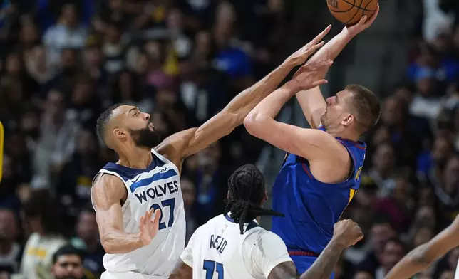 Minnesota Timberwolves center Rudy Gobert, left, goes up to block a shot by Denver Nuggets center Nikola Jokic, right, as Timberwolves center Naz Reid (11) looks on in the second half of Game 1 of an NBA basketball second-round playoff series Saturday, May 4, 2024, in Denver. (AP Photo/David Zalubowski)