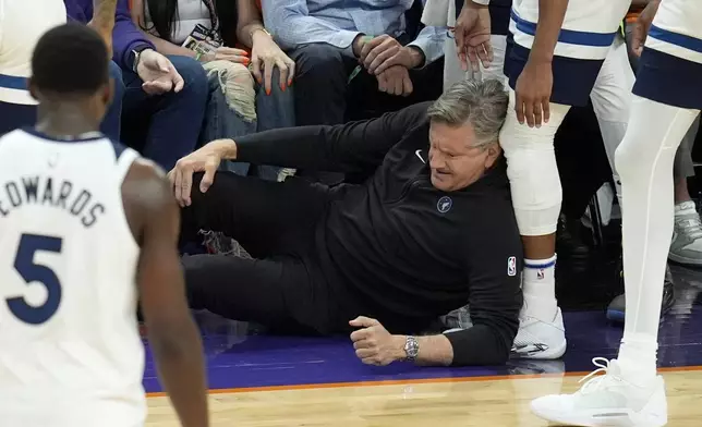 Minnesota Timberwolves head coach Chris Finch holds his knee after colliding with Timberwolves guard Mike Conley during the second half of Game 4 of an NBA basketball first-round playoff series against the Phoenix Suns Sunday, April 28, 2024, in Phoenix. The Timberwolves won 122-116, taking the series 4-0. (AP Photo/Ross D. Franklin)