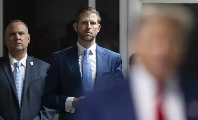 Eric Trump listens as his father, former President Donald Trump, talks with the media outside Manhattan criminal court before his trial in New York, Tuesday, April 30, 2024. (Justin Lane/Pool Photo via AP)
